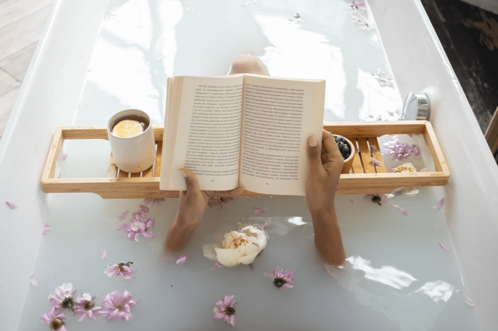 A person reading a book in a bathtub with flowers