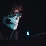 Man wearing a skull mask and working on website security