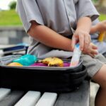 Kid eating his lunch box on a school bench