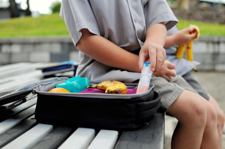 Kid eating his lunch box on a school bench