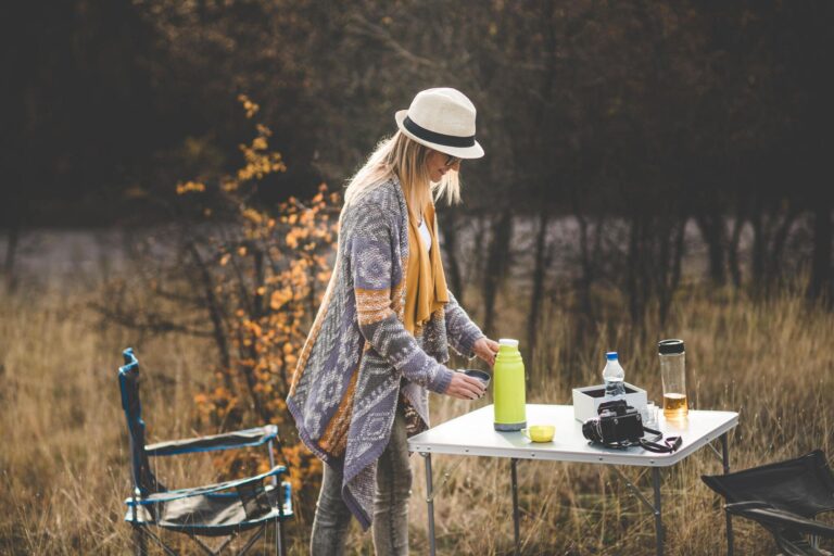 Woman pouring some tea in the tea cup on a camping table