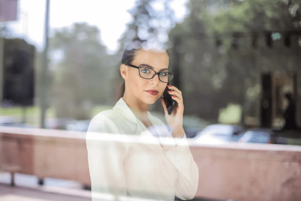 Woman looking through window glass while talking on phone